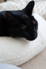 Tuxedo cat napping on the white sherpa Marshmallow Pudding Bed by Ocatnip